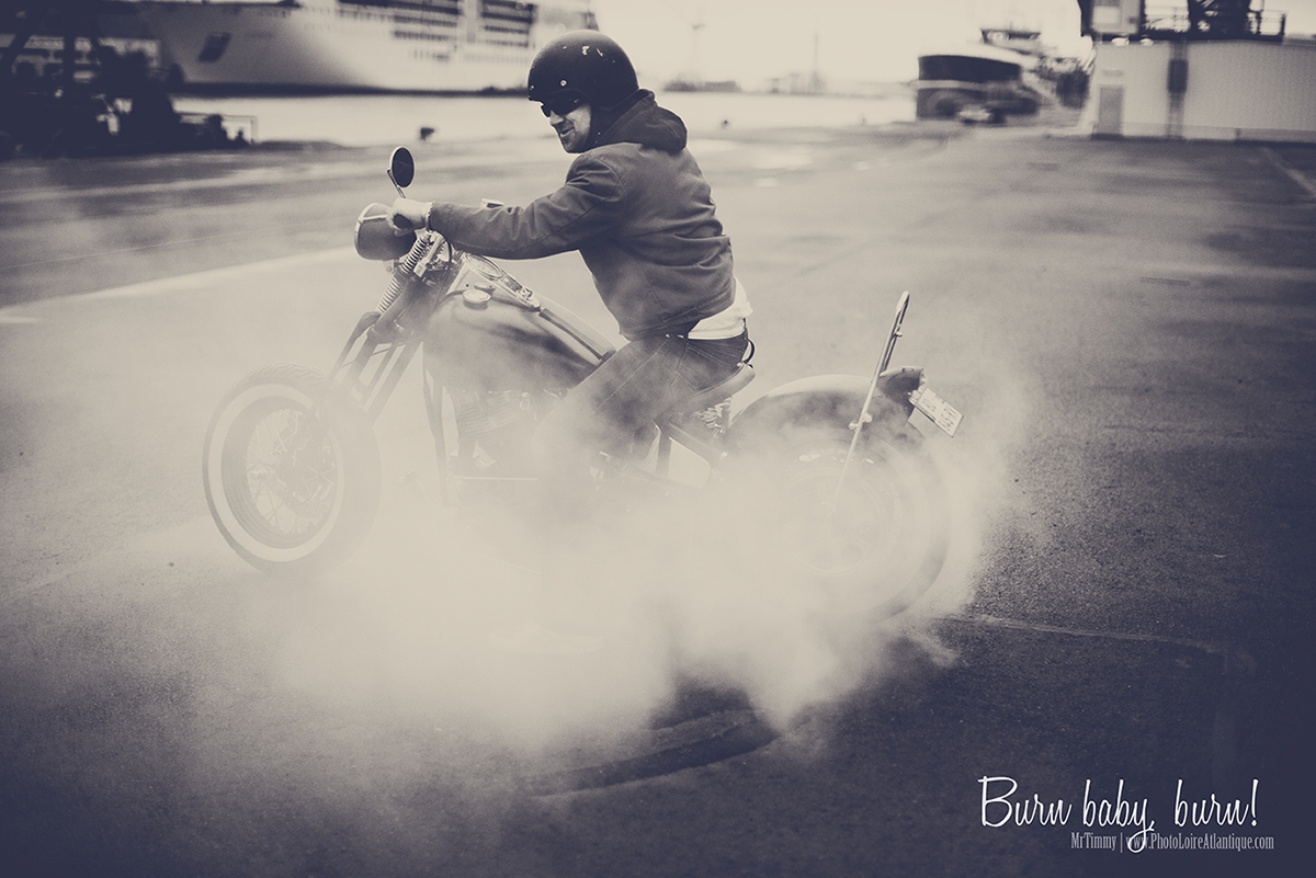 Modèle masculin avec moto ancienne Harley Davidson faisant un burn