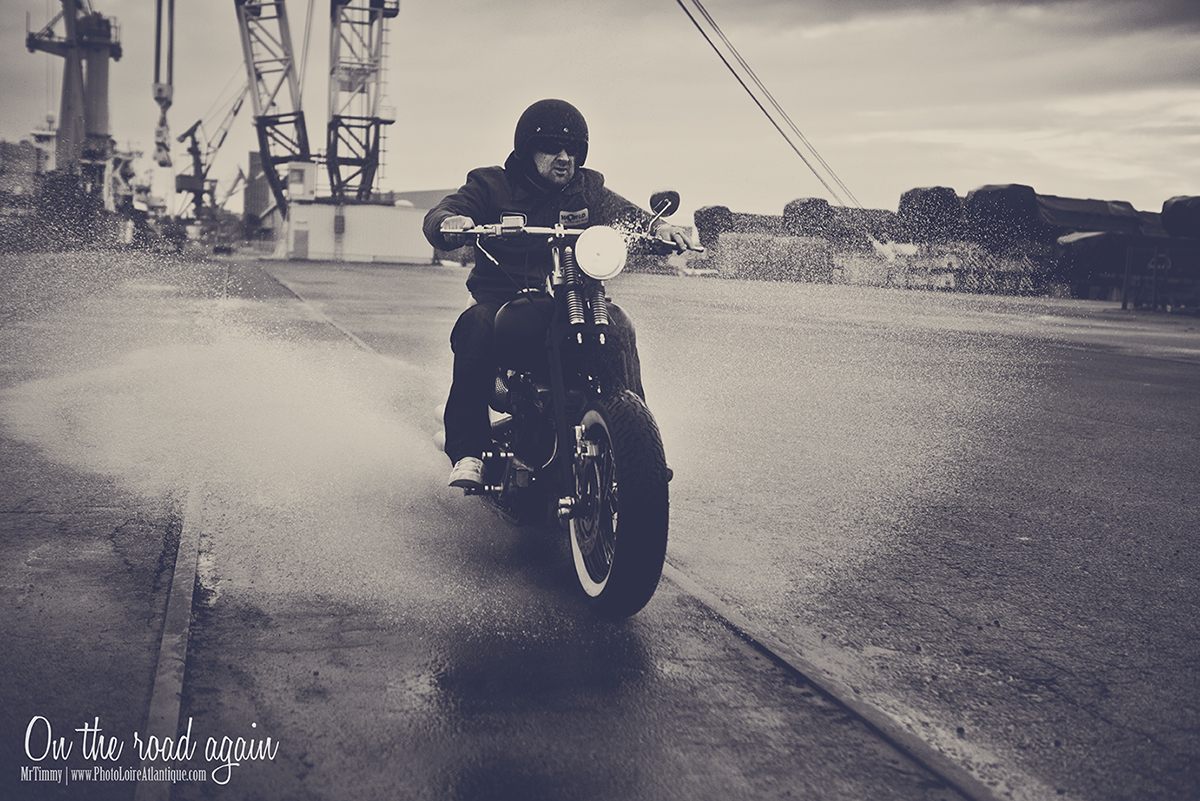 Modèle masculin avec moto ancienne Harley Davidson roulant à haute vitesse dans une flaque d'eau